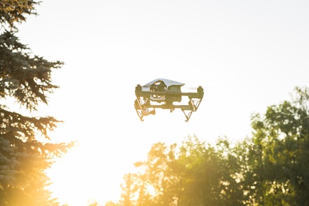 Ufa, Russia. - August 8, 2016: White drone, quadrocopter with photo camera flying in the blue sky.のeditorial素材