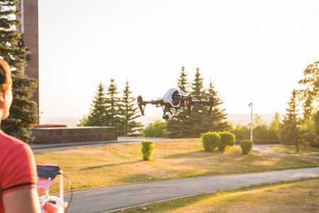 Ufa, Russia. - August 8, 2016: White drone, quadrocopter with photo camera flying in the blue sky.のeditorial素材
