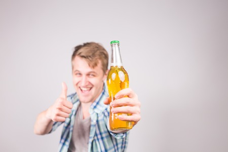 A handsome young man feeling happy showing thumbs up and holding a bottle of beer.の写真素材