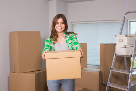 Portrait of woman carrying cardboard box in new house - Moving, new home and people conceptの写真素材