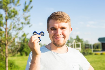Young man holding and playing with fidget spinner. looking at camera.の写真素材