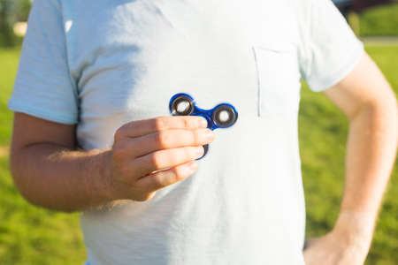 young man playing with a fidget spinner, focus on spinner.の写真素材