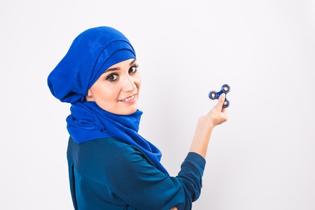 Young beautiful muslim girl holding and playing with fidget spinner. studio shot on white background.の写真素材
