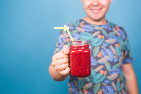 Close up of man holding detox smoothie with drinking straw. Concept of healthy lifestyle, people and foodの写真素材
