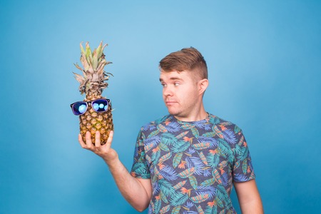 Funny man hold pineapple with sunglasses on blue backgroundの写真素材