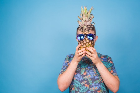 Funny man hold pineapple with sunglasses on blue backgroundの写真素材