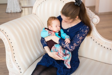 Happy mother holding her sleeping baby son indoors.