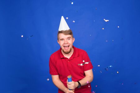 Young funny man celebrating new year and christmas party with confettiの写真素材