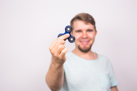 young man playing with a fidget spinner, focus on spinnerの写真素材