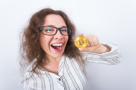 Happy woman showing Golden Bitcoin coin. Virtual money concept. Cryptocurrencyの写真素材