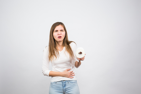 Sick woman with hands pressing her crotch lower abdomen, holding paper roll. Medical problems, incontinence, health care conceptの写真素材