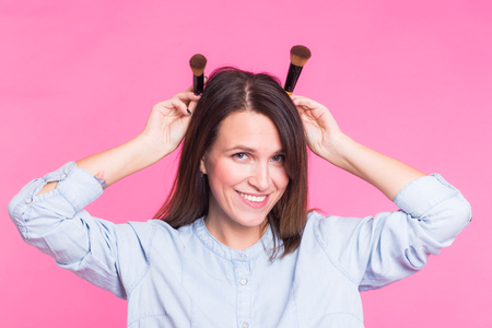 Funny makeup artist with brushes on pink backgroundの写真素材