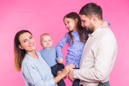 Cute family posing and smiling at camera together on pink backgroundの写真素材