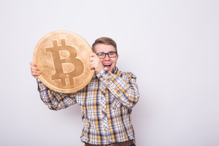 Happy business man holding big golden bitcoin on white background. Crypto currency, virtual money, internet and economics conceptの写真素材