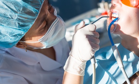 Close-up portrait of a female patient at dentist in the clinic. Teeth whitening procedure with ultraviolet light UV lamp.の写真素材