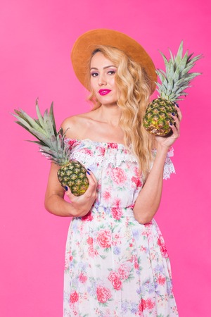 Happy young woman holding a pineapple on a pink background. Summer, diet and holidays conceptの写真素材