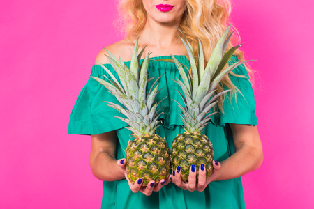 Close up of woman holding a pineapple on a pink background. Summer, diet and holidays conceptの写真素材