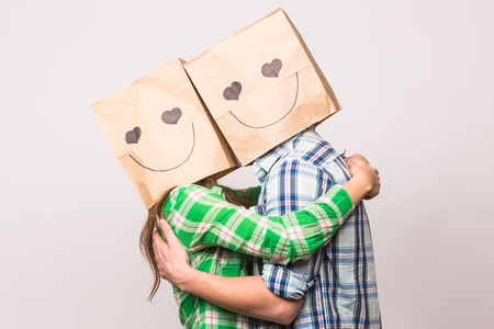 Love couple covering their faces with paper bag over white backgroundの写真素材
