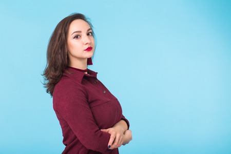 Portrait of serious casual brunette caucasian businesswoman wearing standing on blue background with copy spaceの写真素材