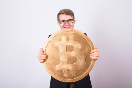 Businessnan holding big golden bitcoin on pink background. Crypto currency, virtual money, internet and economics conceptの写真素材