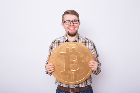 Cheerful man holding gold bitcoin - popular cryptocurrency, virtual moneyの写真素材