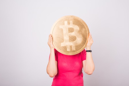 Golden Bitcoin in a woman hand, Digital symbol of a virtual cryptocurrency.の写真素材