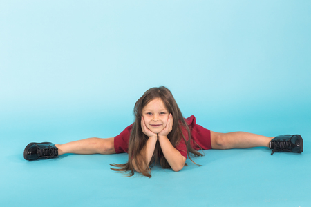 portrait of cute little ballerina doing splits isolated on blue backgroundの写真素材
