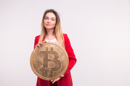 Freckled woman holding big bitcoin on white background. Cryptocurrency investment concept.の写真素材