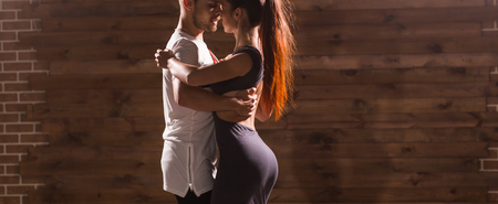 Young couple dancing social danse kizomba or bachata or semba or taraxia in dancing class background