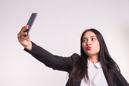 Young asian woman making selfie in studio on white background
