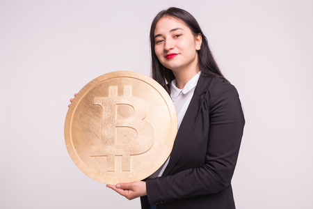 Asian woman holding big bitcoin on white background. Cryptocurrency investment concept.の写真素材