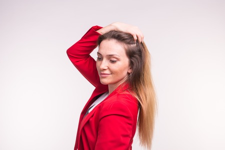 portrait of young beautiful woman posing in red suit with hand above.の写真素材