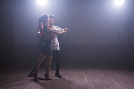 Skillful dancers performing in the dark room under the concert light and smoke. Sensual couple performing an artistic and emotional contemporary danceの写真素材