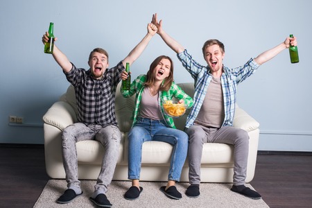 Happy friends or football fans watching soccer on tv and celebrating victory. Friendship, sports and entertainment conceptの写真素材