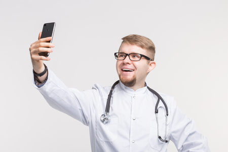 Happy male doctor making selfie in studioの写真素材