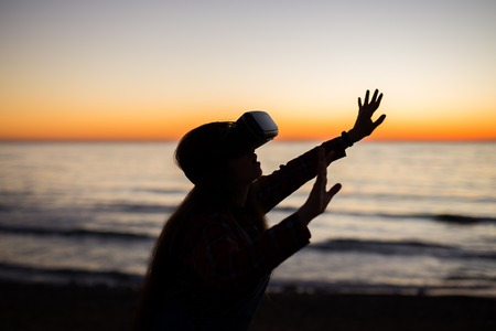 Virtual Realty is here woman wearing virtual reality glasses on the over beautiful sea and sky backgroundの写真素材