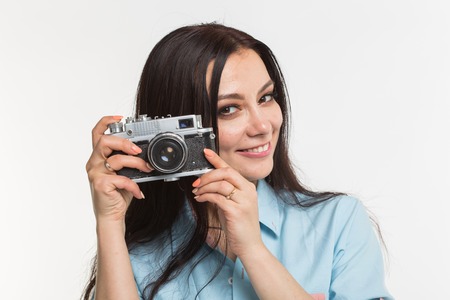 Photographer, hobby and people concept - Young brunette woman with retro camera on white background