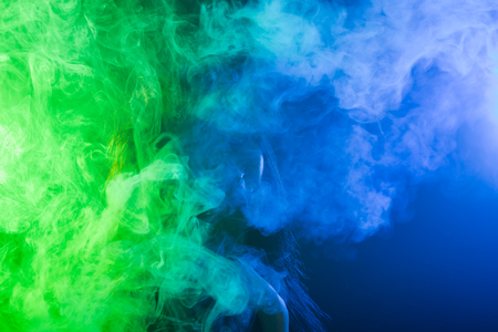 Young woman in neon light and smoke of e-cigarettes or vapeの写真素材