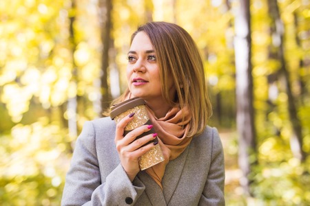 Autumn, drink and people concept- Close up portrait of young beautiful woman in grey coat with coffeeの写真素材