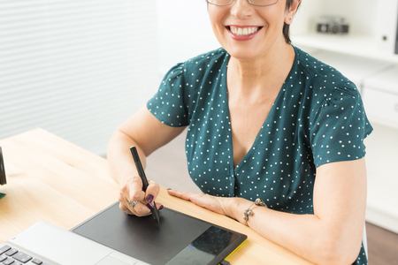 Business, technology and people concept - Close up of happy woman using graphics tabletの写真素材