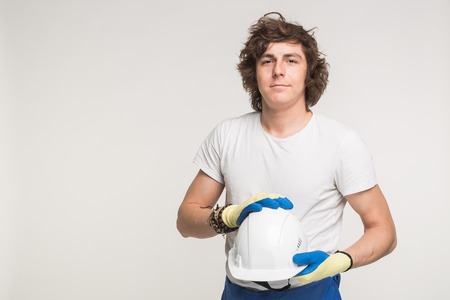 Portrait of curly caucasian male builder with helmet on white background with copy space