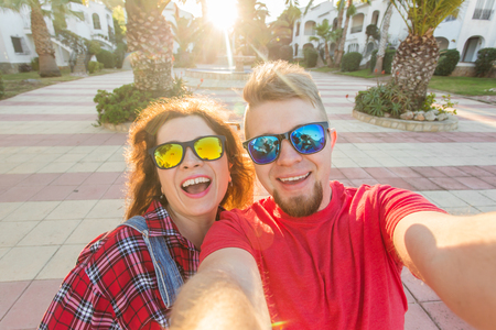 Travel, vacation and holiday concept - Funny couple in sunglasses having fun and taking selfieの写真素材