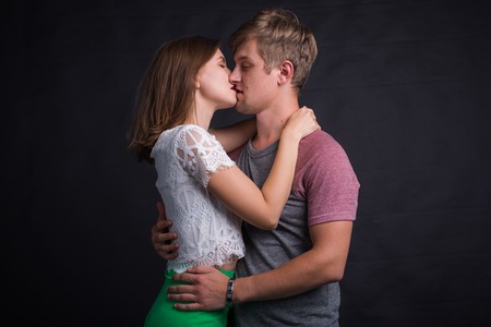 Beautiful young couple hugging and kissing isolated on black background.の写真素材