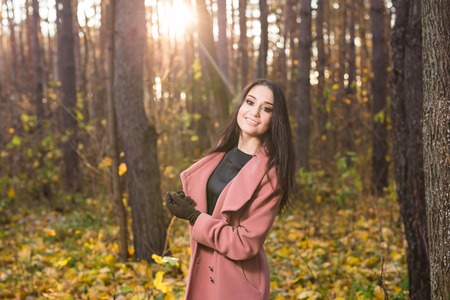 Season, fall and people concept - beautiful young woman walking in autumn park