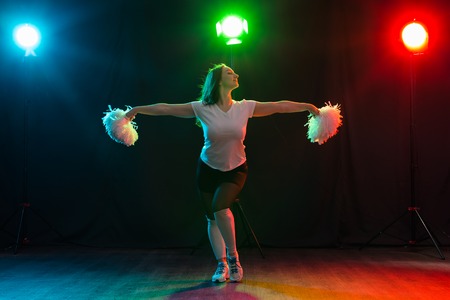 Full length portrait of cheerleader dancing with pom-pomsの写真素材