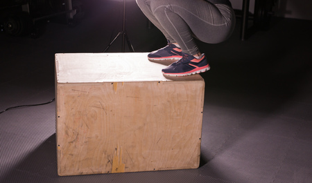 Young woman jumping on box at a crossfit gym.