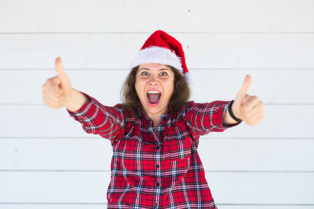 Christmas and people concept - woman in christmas hat showing thumbs upの写真素材