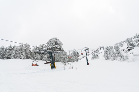 Ski lifts and cable cars going up the mountain bringing snowboarders to ski slopes.の写真素材