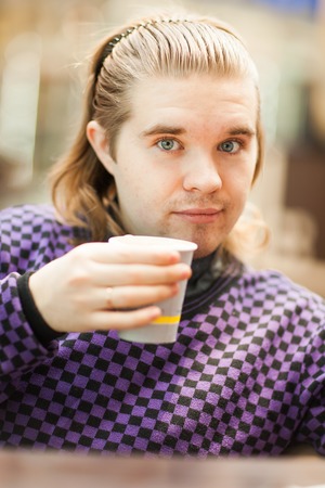 A stylish young man drinks hot coffee.