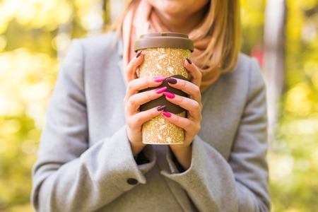 Autumn, nature and people concept - Close up of woman in grey coat holding a cup of coffeeの写真素材
